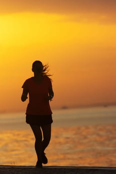 Silhouette of young woman are exercising running on the river. Healthy running and outdoor jogging, morning