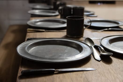 Old antique dishes - metal retro plates and knifes on the table - battleship equipment