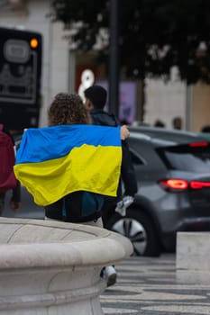 10-29-2022 LISBON, PORTUGAL: Ukrainian protest in Lisbon - a woman with a Ukrainian flag behind her back. Mid shot