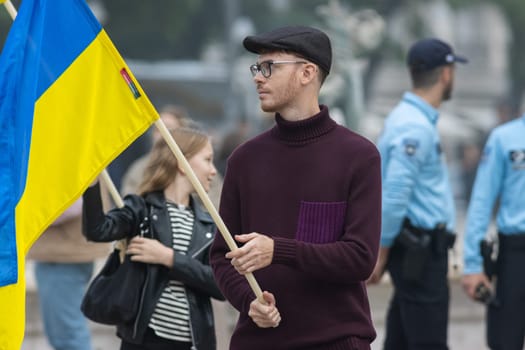 10-29-2022 LISBON, PORTUGAL: Ukrainian protest in Lisbon - a young man holding a Ukrainian flag. Mid shot