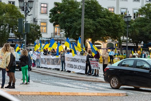 10-29-2022 LISBON, PORTUGAL: Ukrainian protest in Lisbon - people are holding Ukrainian flags and protest posters standing next to the roadway. Mid shot