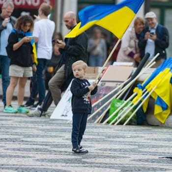 10-29-2022 LISBON, PORTUGAL: Ukrainian protest in Lisbon - a little boy holds a Ukrainian flag in the square during a protest. Mid shot