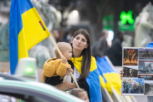 10-29-2022 LISBON, PORTUGAL: Ukrainian protest in Lisbon - young woman with a baby holding the Ukrainian flag. Mid shot