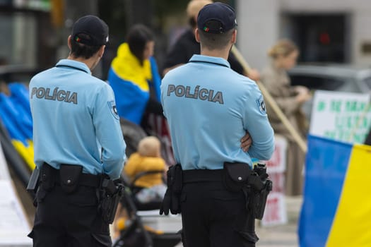 Two police officers stand at the protest of the Ukrainian rally in Portugal. Mid shot