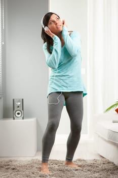 young long haired woman with headphones dancing in her living room