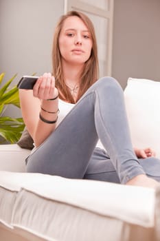 serious sexy girl with a mobile on a couch with intense look