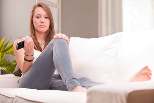 serious sexy girl with a mobile on a couch with intense look