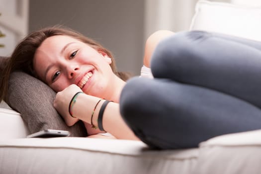 young happy brunette lying on a couch in her living room