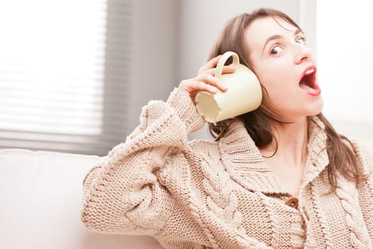 girl listening to a mug making funny faces pretending to hear something amazing