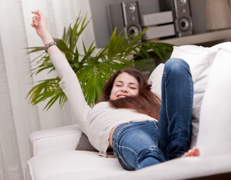 girl happily waking up on her sofa and yawning while stretching