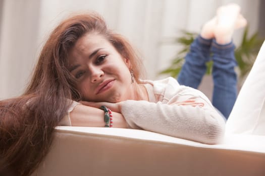young pretty girl lying on a couch and smiling on her living room because her life is good