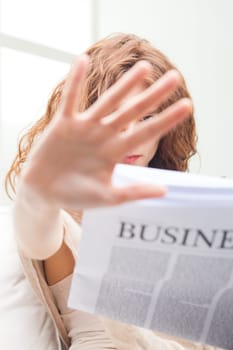 young attractive woman hiding herself behind her hand, she was reading a business newspaper