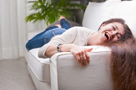 LOL how much could this girl laugh before she could breathe we don't know but she has rings on her hands and a toothy smile that's lovely and she's on a white couch in her living room and she has long brown hair