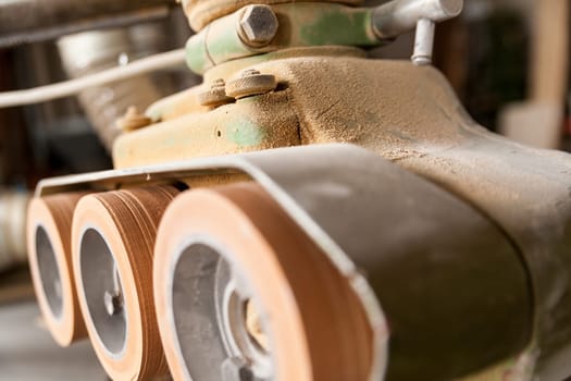 detail of machinery wheels in a woodworker workshop covered with sawdust