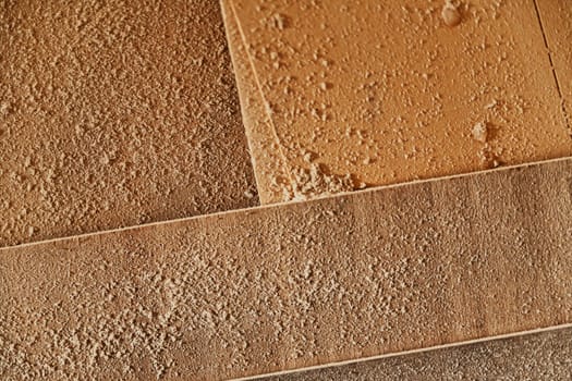 Fresh sawdust lying on panels of wood in a workshop viewed from above in a full frame texture