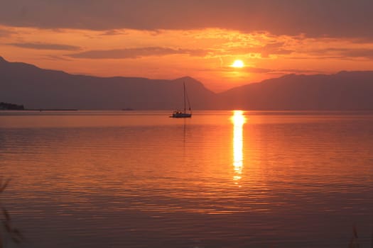 Scenic sunset and a lonely sailboat at the coast of Trogir, Croatia