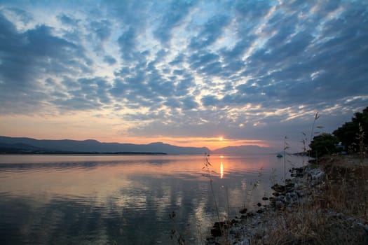 Scenic sunset and a lonely sailboat at the coast of Trogir, Croatia