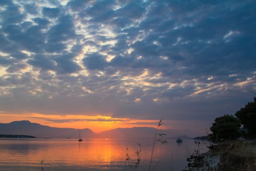 Scenic sunset and a lonely sailboat at the coast of Trogir, Croatia