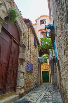 Scenic narrow, typical mediterranean alley in downtown Trogir, Croatia