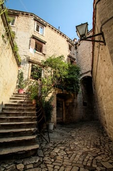 Scenic narrow, typical mediterranean alley in downtown Trogir, Croatia