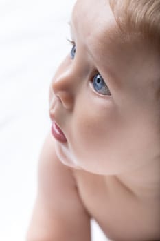 Portrait of an adorable innocent newborn blue eyed baby in a close up cropped side view of the face over a high key white background
