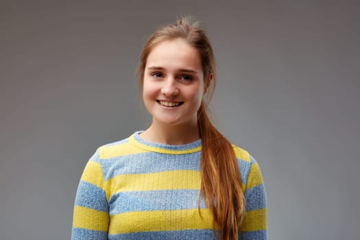 young beautiful woman in yellow striped sweater smiles pretty moderately