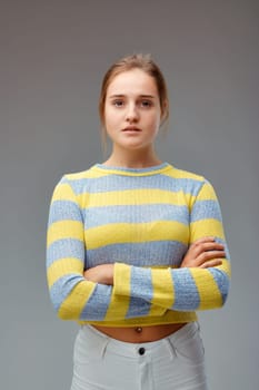 Strong and beautiful. Portrait of a young woman with a yellow striped sweater, her arms folded and a proud and determined look.