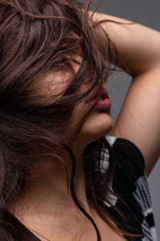 Sensual young woman with her long hair covering her face posing with arm up, eyes closed and parted lips in a close up cropped profile portrait