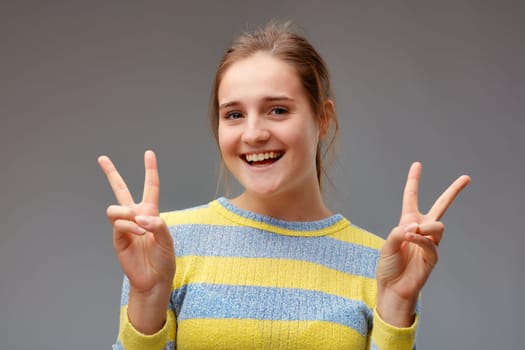 I double won! portrait of smiling young woman making victory gesture with the two hands