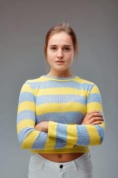 Strong and beautiful. Portrait of a young woman with a yellow striped sweater, her arms folded and a proud and determined look.