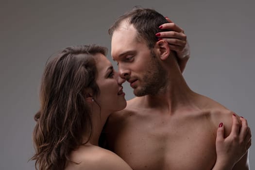 confident man and woman in love, she gently caresses the nape of his neck and brings him to her by touching the skin of his shoulder as their gazes cross in an infinite flow of love