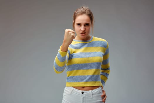 Menacing young woman, show the fist with which she will hit you to punish you and take revenge for what you did to her! Rascal!