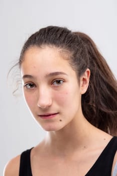 Thoughtful earnest young woman staring at the camera with a serious calm expression in a close up head shot on white