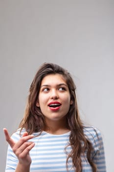 Young woman having a eureka moment of inspiration as she suddenly has a bright idea or finds the solution to a problem over a grey studio background