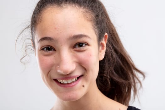 Cheerful young woman grinning at the camera with a happy expression in a close up cropped head shot on white