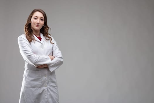 Confident female doctor or consultant in a white lab coat standing with crossed arms looking at camera with a quiet smile