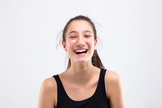 Laughing vivacious happy young woman with her long hair tied back in a pony tail in a head and shoulders studio portrait