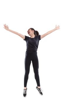 Exuberant laughing vivacious young woman jumping for joy with outstretched arms isolated full length on white