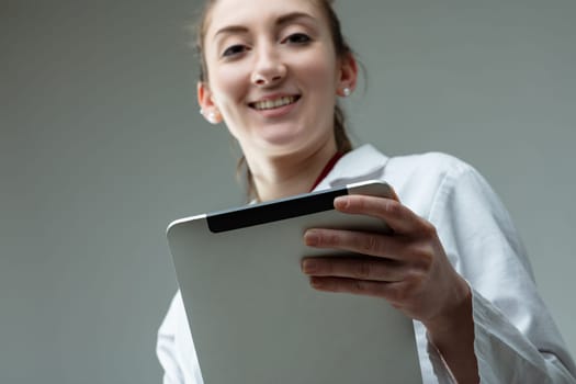 Smiling doctor or nurse holding a clip board with patient notes in a low angle view with focus to her hand