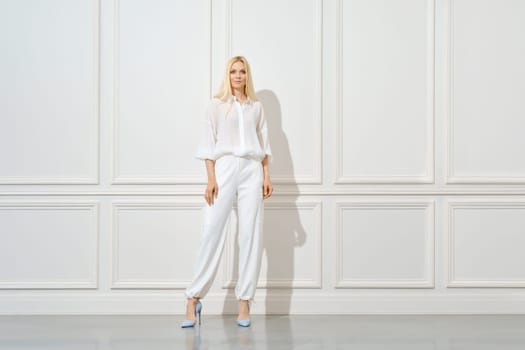 Confident blonde woman in total white outfit