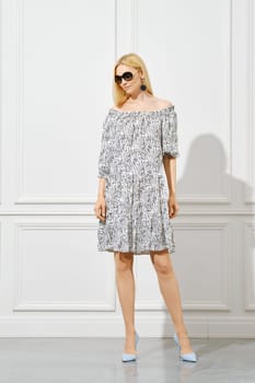 Beautiful woman in three-quarter sleeve sundress posing in bright room