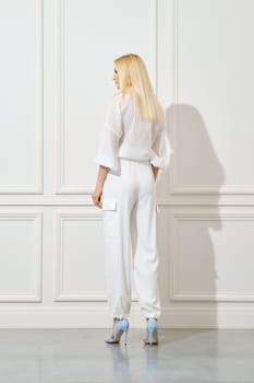 Back view of a woman in white cotton shirt and trousers