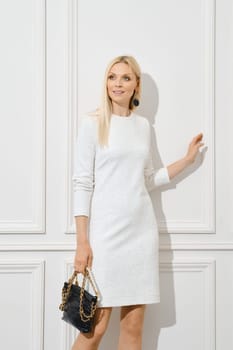 Cheerful blonde woman in short white dress with handbag