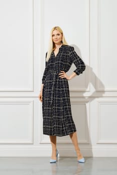 Stylish blonde woman in woollen patterned dress indoors