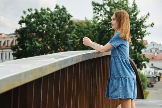 Woman leaning on a railing and surveys neighbourhood from height of bridge