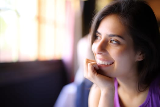 Happy beauty woman looking through a window in a house interior