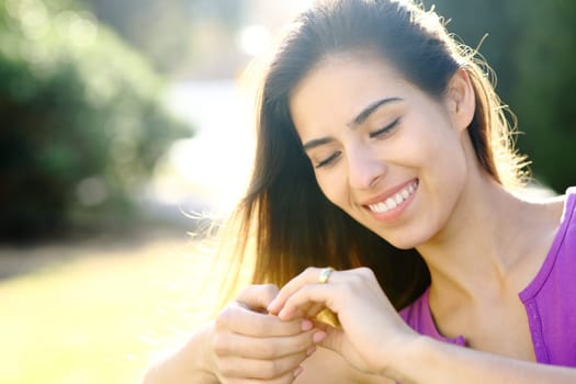Happy fiancee looking at engagement ring in a park