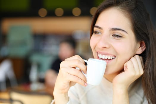 Happy woman drinking coffee and laughing in a restaurant interior
