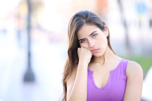 Bored woman looking at camera standing alone in the street
