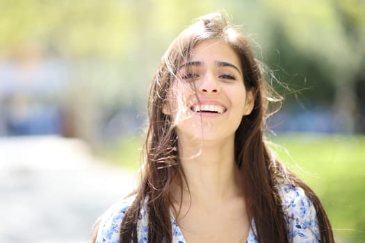 Front view portrait of a happy woman laughing with tousled hair a windy day
